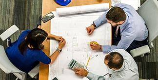 An areal image of three people collaborating at a desk